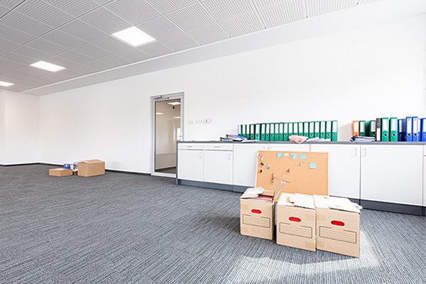 Cardboard boxes and binders in a partially moved office space.